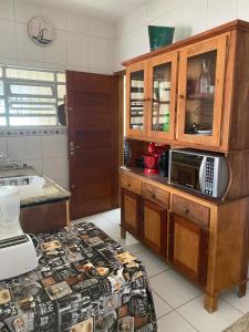 uma cozinha com um micro-ondas num armário de madeira em Casa do lado da praia, 100 metros da praia. em Mongaguá