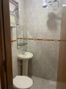 a bathroom with a white toilet and a sink at Casa do lado da praia, 100 metros da praia. in Mongaguá