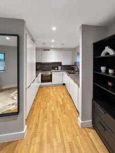 a kitchen with white cabinets and a wooden floor at Luxury 1 bedroom Apartment in London overseeing Canary Wharf with free parking in London