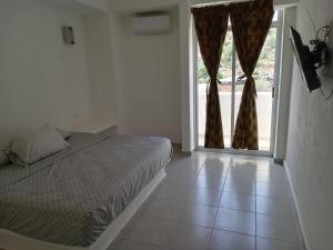 ein Schlafzimmer mit einem Bett und einem großen Fenster in der Unterkunft Hotel Ixtazihua JP in Zihuatanejo
