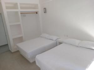 zwei Betten in einem Zimmer mit weißen Wänden in der Unterkunft Hotel Ixtazihua JP in Zihuatanejo