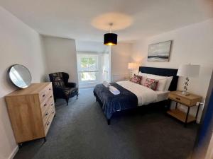 sypialnia z łóżkiem, krzesłem i komodą w obiekcie Lime Tree in blue Duplex Serviced Apartment w Cambridge