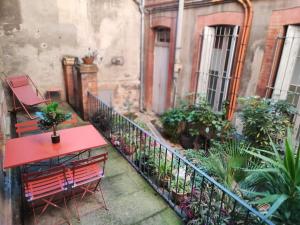 a red table and bench on a balcony with plants at ► BNB TOULOUSE ► Le Ravissant de Jeanne d'Arc • WiFi • 24/24h • in Toulouse