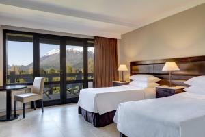 a hotel room with two beds and a balcony at Arelauquen Lodge, a Tribute Portfolio Hotel in San Carlos de Bariloche