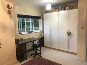 a home office with a desk and a refrigerator at Serene spacious room (double) in gorgeous bungalow on river near Thorpe park and Holloway University Egham in Staines upon Thames
