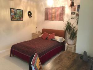 a bedroom with a bed and a potted plant at Serene spacious room (double) in gorgeous bungalow on river near Thorpe park and Holloway University Egham in Staines upon Thames