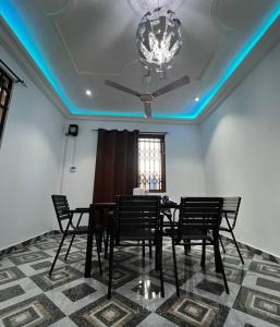 una sala da pranzo con tavolo, sedie e lampadario pendente di Serene Getaway: 5-bedroom Duplex a Dawhwenya