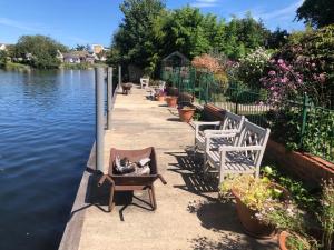 a row of chairs sitting next to a body of water at Serene spacious room (double) in gorgeous bungalow on river near Thorpe park and Holloway University Egham in Staines upon Thames