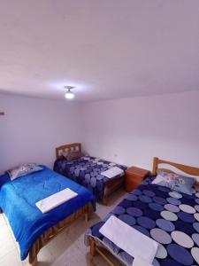 three beds in a room with blue sheets at Hacienda Norabuena in Recuay