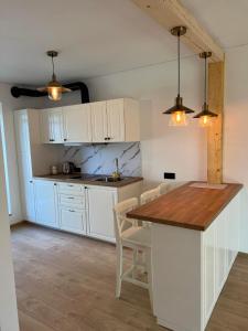 a kitchen with white cabinets and a wooden table at Rekvila in Šiauliai