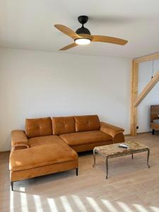 a brown couch in a living room with a ceiling fan at Rekvila in Šiauliai