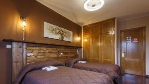 a bedroom with two beds and a wooden wall at H Rural Chamouco in Bóveda +13 photos