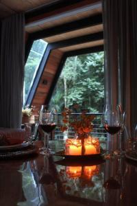 einen Tisch mit Gläsern Wein und ein Fenster in der Unterkunft Chalé Romântico com cachoeira in Witmarsum