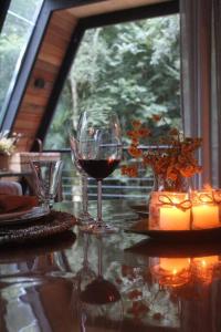dos copas de vino sentadas en una mesa frente a una ventana en Chalé Romântico com cachoeira, en Witmarsum