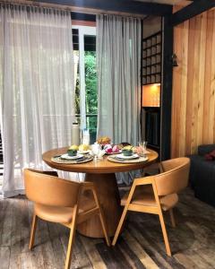una mesa de madera con 2 sillas y una mesa con comida. en Chalé Romântico com cachoeira, en Witmarsum