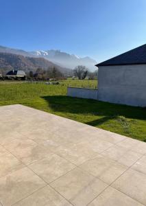a patio with a grass field and a building at Maison au cœur des Pyrénées ! in Ayzac-Ost