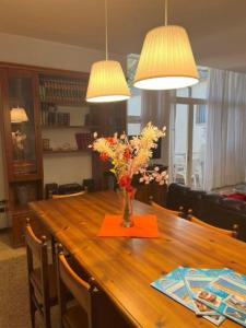 una mesa de comedor con un jarrón de flores. en Elegant villa in a quiet area with garden en Bibione