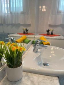 un lavabo con un jarrón con flores. en Elegant villa in a quiet area with garden en Bibione