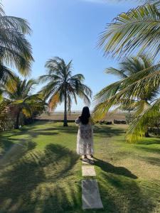 a woman standing on a path under a palm tree at casa moderna con playa cartagena in Cartagena de Indias