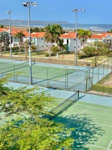 two tennis courts with palm trees and the ocean at casa moderna con playa cartagena in Cartagena de Indias