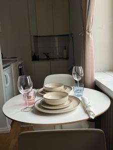 una mesa blanca con platos y copas de vino. en Your Chic Vibrant Airbnb en Helsinki