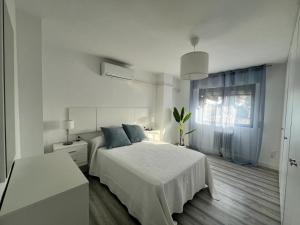 Habitación blanca con cama y ventana en H&H Apartamento Azucena en Granada