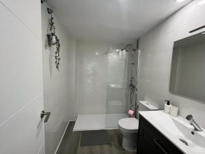 Baño blanco con aseo y lavamanos en H&H Apartamento Azucena en Granada