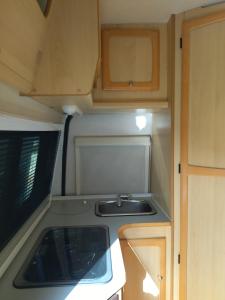 una cocina con fregadero y armarios de madera en alquiler autocaravana Camper en Cehegín