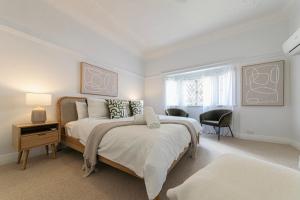 a white bedroom with a bed and a chair at Urban Getaway Bardon Luxe 4 bed 3 bath + pool in Brisbane