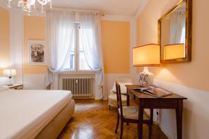 een slaapkamer met een bed, een bureau, een bed en een raam bij Ponte Vecchio Escape Suite in Florence