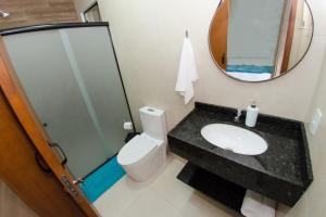 een badkamer met een wastafel, een toilet en een spiegel bij Pousada Viva praia 30 metros da Praia in Penha