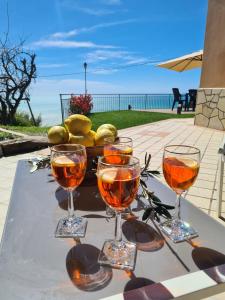 three wine glasses on a table with a bowl of lemons at Casa Ulivi e Mare in Ventimiglia