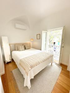 um quarto branco com uma cama grande e uma janela em Largo Inn Suites Evora em Évora
