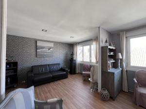 a living room with a black couch and two windows at La Terrasse in Le Crotoy