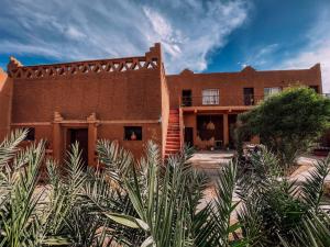 a house in the desert with plants in front of it at Dar Talmoudi ,Traditional Riad, Local Food, Camel , Desert Excursions in Tagounite