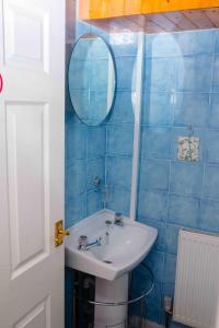 a blue tiled bathroom with a sink and a mirror at THE CHADWICK in Skegness