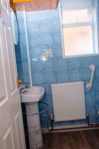 a blue tiled bathroom with a sink and a window at THE CHADWICK in Skegness