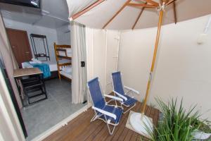 twee blauwe stoelen op een veranda met een paraplu bij Pousada Viva praia 30 metros da Praia in Penha