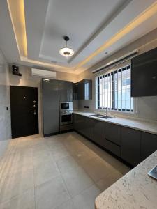 a large kitchen with black cabinets and a sink at Airserenity Stay in Kwedonu