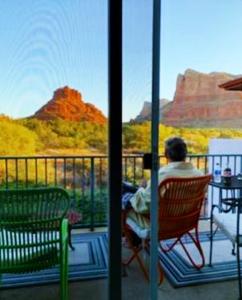 a man sitting in a chair on a balcony looking out at the canyon at Cozy Cactus Resort sorta-kinda in Sedona