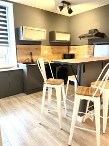 eine Küche mit 2 Stühlen und einem Tisch mit einem Waschbecken in der Unterkunft Meublés déco Fab - Tapas in Luxeuil-les-Bains