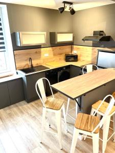 eine Küche mit einem Tisch, Stühlen und einem Waschbecken in der Unterkunft Meublés déco Fab - Tapas in Luxeuil-les-Bains