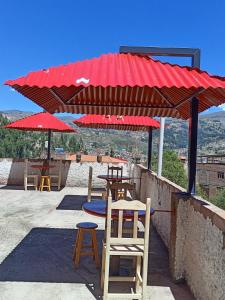 un patio con mesas y sillas bajo un techo rojo en Amazing Huaraz, en Huaraz