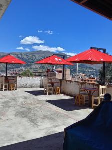 un patio con sombrillas rojas, mesas y sillas en Amazing Huaraz, en Huaraz