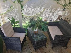 un patio con sillas de mimbre y una mesa con una planta en Gîte L'instant Cocooning, en Baie-Mahault