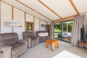 a living room with two couches and a table at Finlay Waterfront - Waikawa Holiday Home in Picton