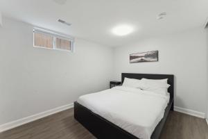 a white bedroom with a bed and a window at Modern 3BR Suites in Ottawa