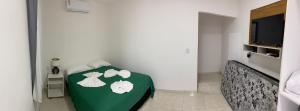 een kamer met een bed met een groene deken bij Quatro Estações in Mata de Sao Joao
