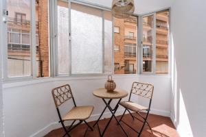 a table and two chairs in a room with windows at Apartamento Carmen in Almuñécar +12 photos