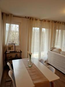 ein Wohnzimmer mit einem Tisch, einem Bett und Fenstern in der Unterkunft Cozy apartment near Paris in Clamart